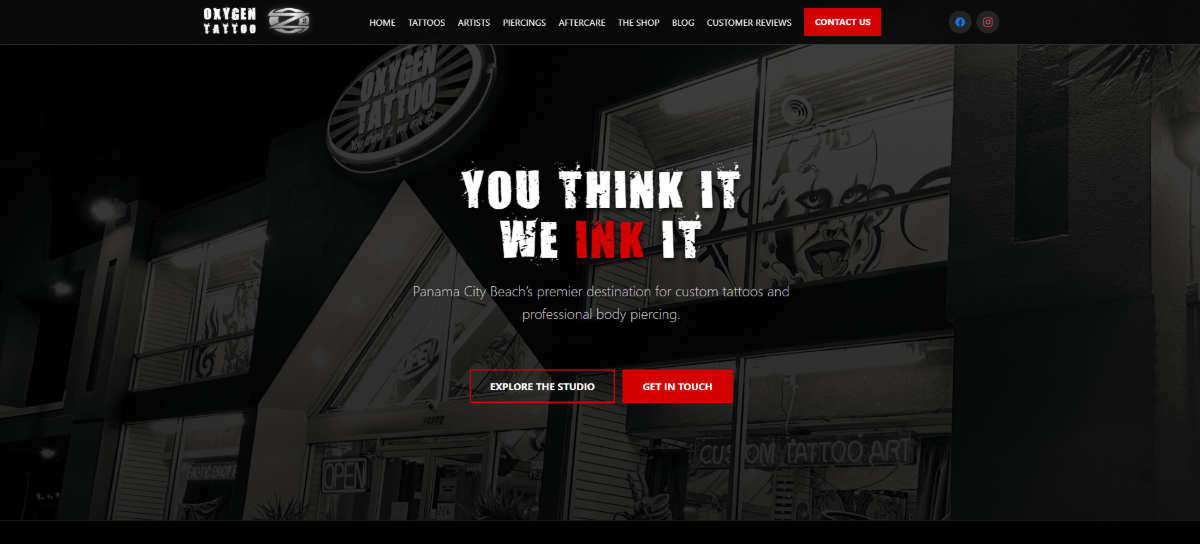 The homepage hero section for Oxygen Tattoos on desktop is a static design. There’s a photo of the shop in the background with a dark overlay. The headline reads “You Think It We Ink It” and there’s a short description that follows. There are also two call-to-action buttons — “Explore the Studio” and “Get in Touch”.