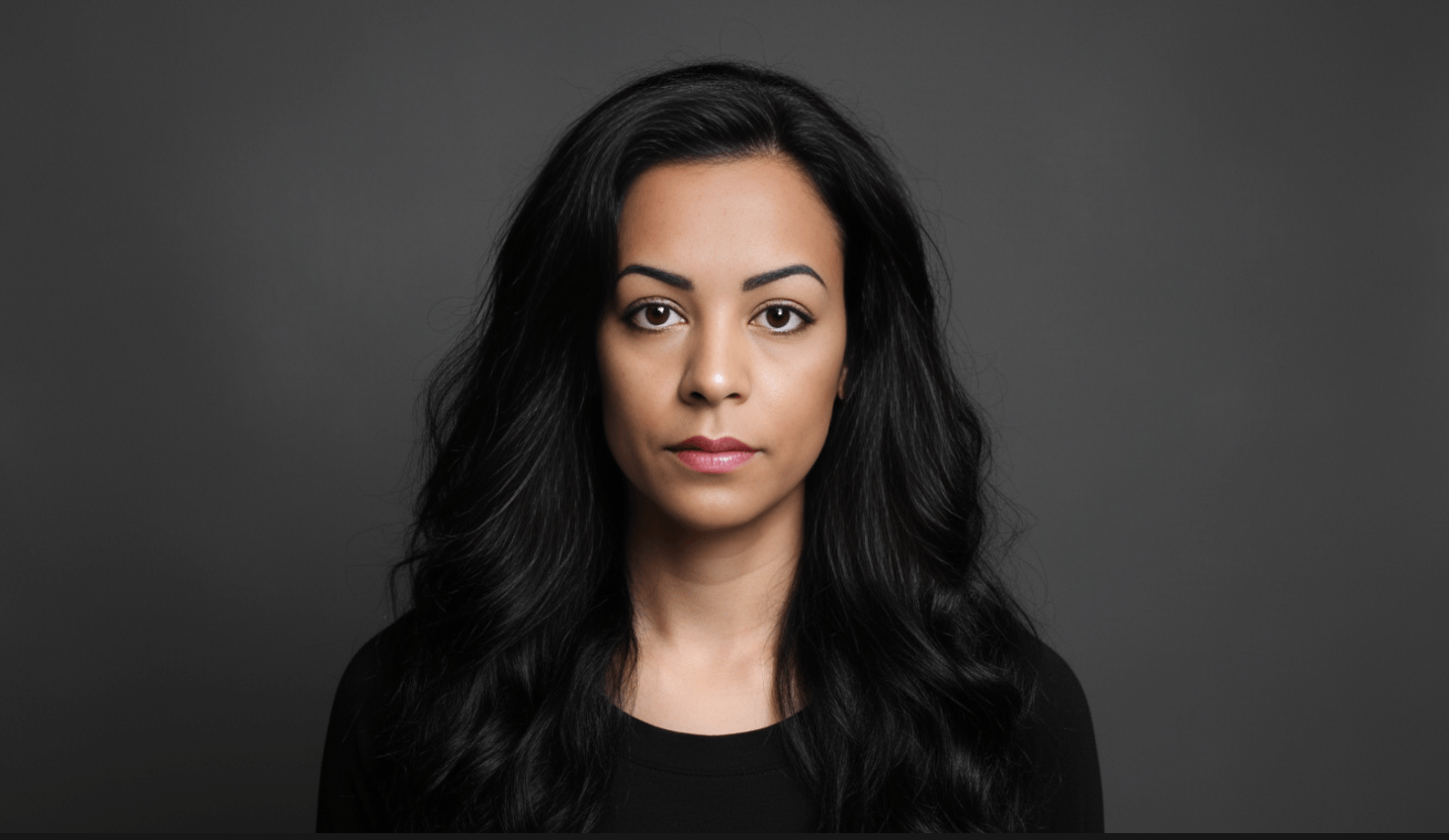 Woman with tan skin and dark hair in dark shirt