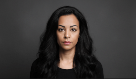 Woman with tan skin and dark hair in dark shirt